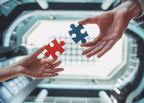Close-up of business people wanting to put two pieces of puzzle together.