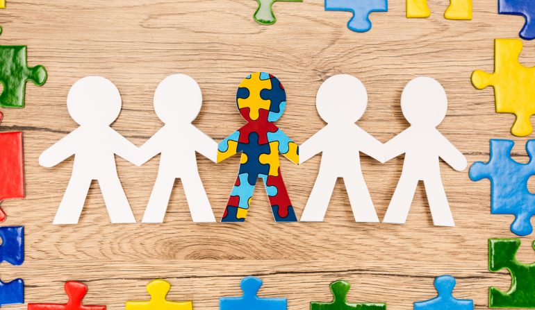 Top view of bright pieces of puzzle and special kid with autism among another on wooden background